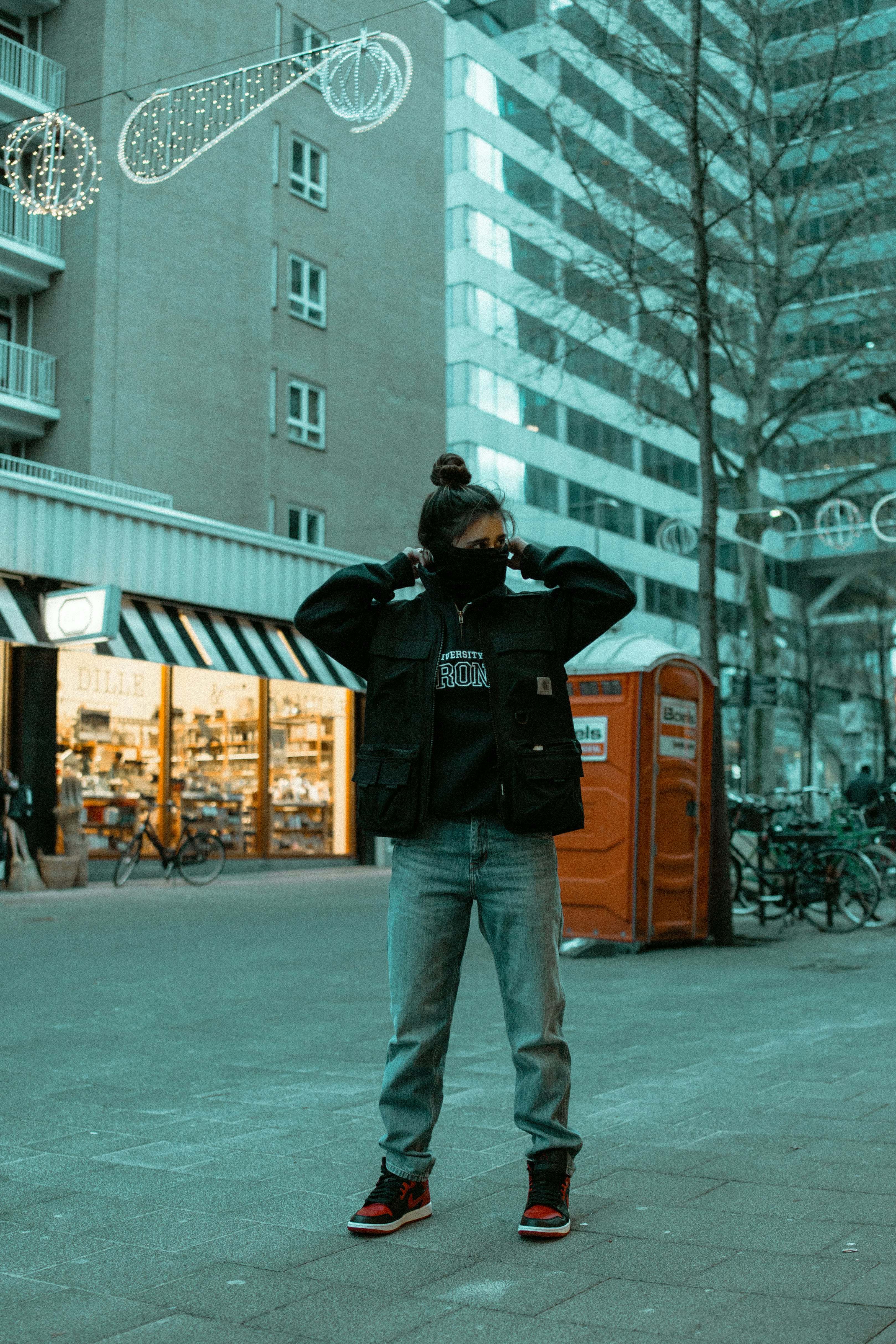 man in black jacket and blue denim jeans standing on sidewalk during daytime